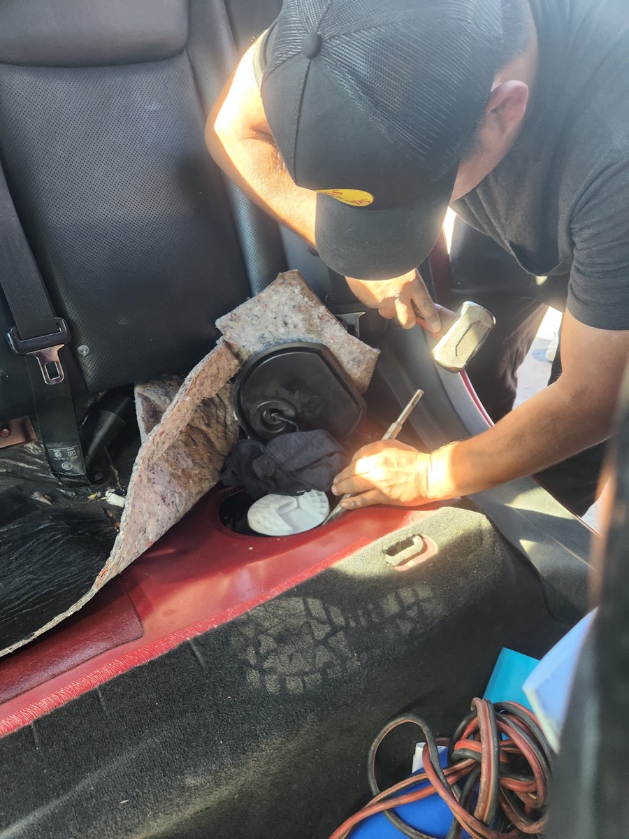 A mechanic working on a fuel pump inside a car
